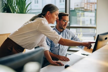 Photo of two colleagues in front of a desktop computer